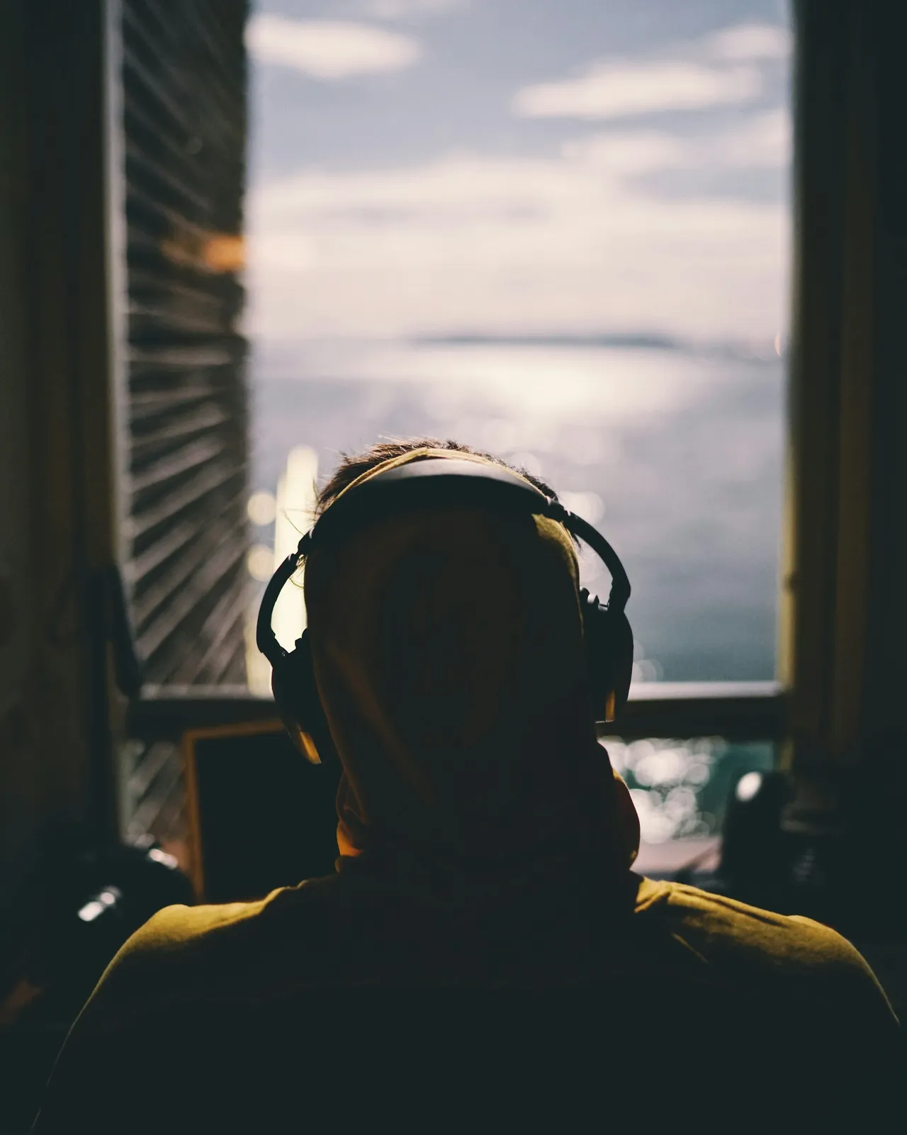 Young person with headphones at a window