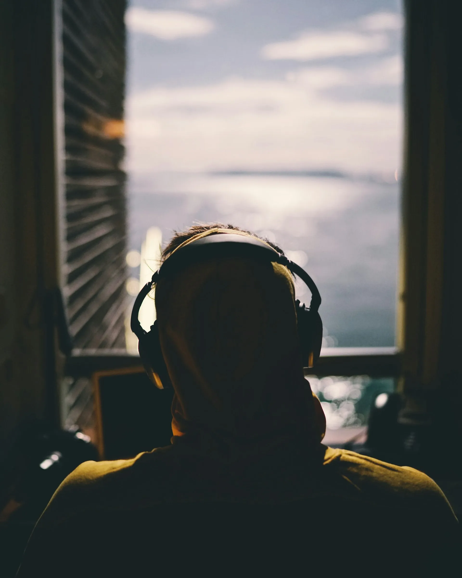 Young person with headphones at a window