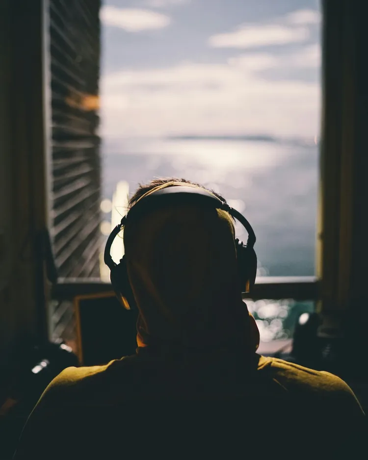 Young person with headphones at a window